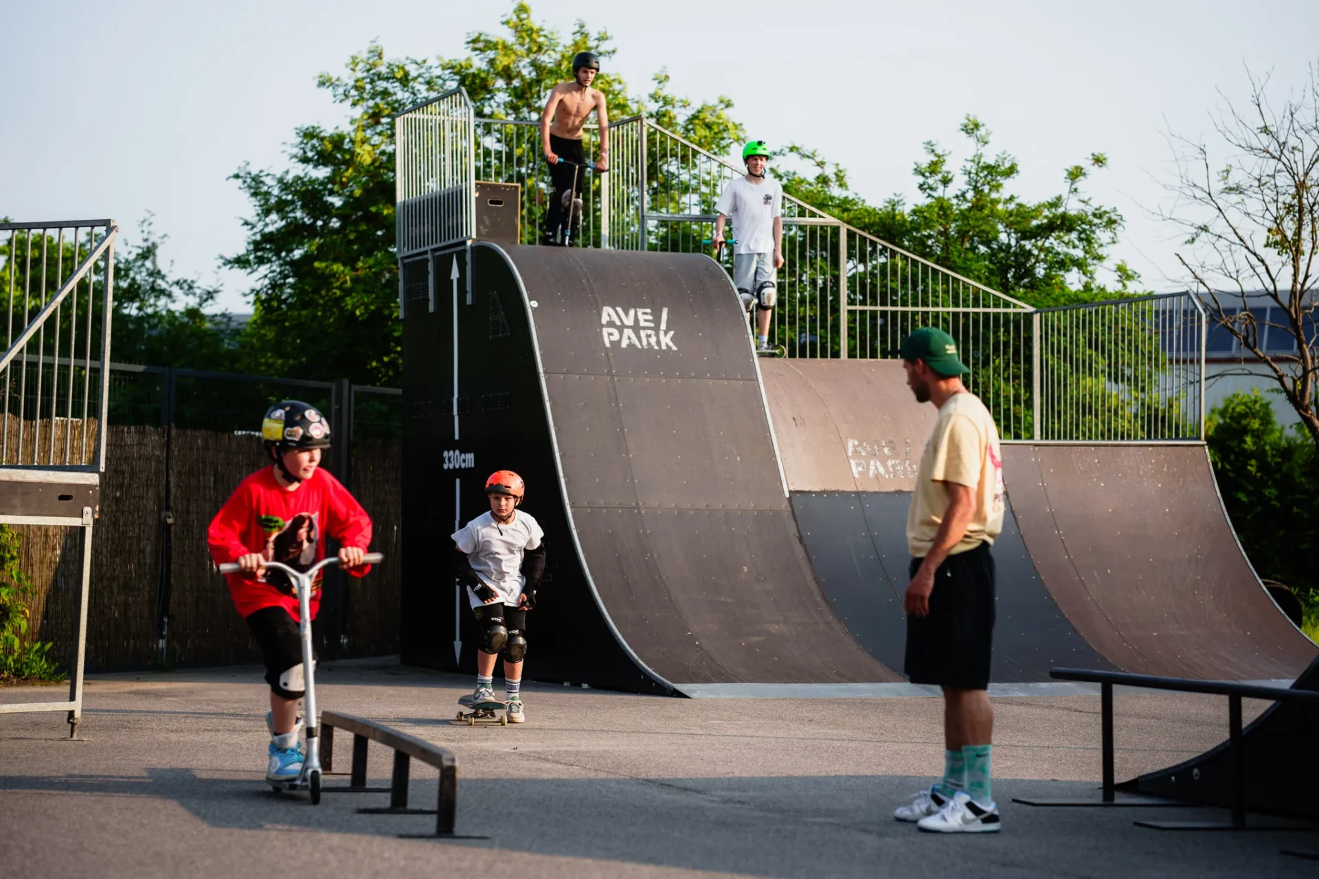 Instruktor obserwuje dzieci przy dużej rampie w skateparku Ave Park